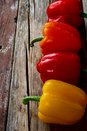 Fresh colorful bell peppers over rustic wooden background.の写真素材
