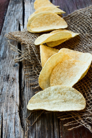 Potato chips on jute and wooden texture.の写真素材