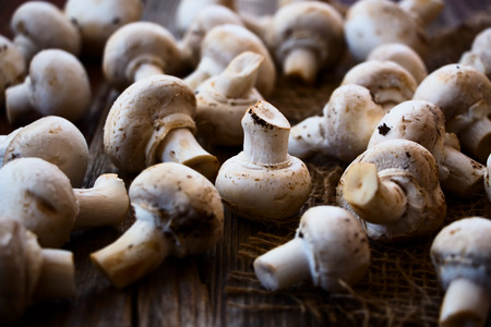 Harvest of White Mushrooms on jute and wooden texture. Selective focus.の写真素材