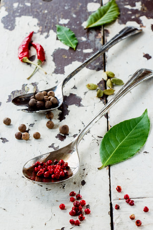 Spices and herbs in vintage metal spoons on old wood texture. Selective focus.の写真素材