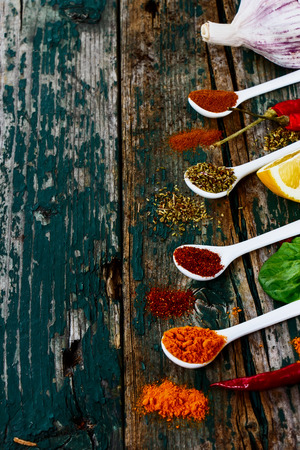 Spices and herbs assortment on spoons over wooden background. Vegetarian food, health or cooking concept. Selective focus.の写真素材