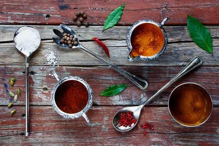Vintage metal spoon and cups with herbs and spices selection on old wood texture. Food background. Top view.の写真素材