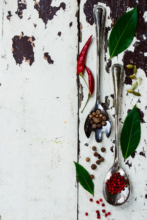 Different herbs and spices in vintage metal spoons on old wood texture with copy space. Top view.の写真素材