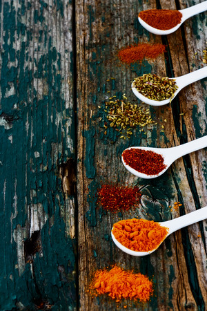 Various spices in spoons on rustic wooden background.の写真素材