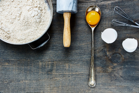 Background with baking ingredients - egg yolk, flour and rolling pin on wooden texture. Top view.の写真素材