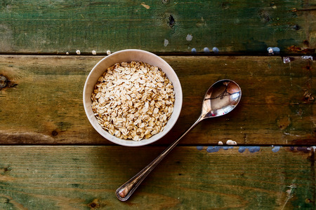Top view of Oatmeal in bowl and vintage spoon on rustic wooden background.の写真素材