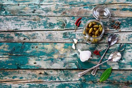 Top view of olives in glass jar with herbs and spices on rustic wooden texture. Background with space for text.の写真素材