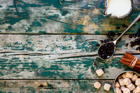 Coffee beans in vintage spoon, milk and sugar in vintage cups on rustic wooden table. Background with space for text.の写真素材