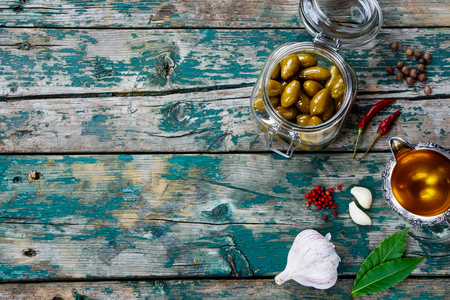 Olives in jar and Olive Oil on rustic wooden tablel - italian food concept. Background with space for text.の写真素材