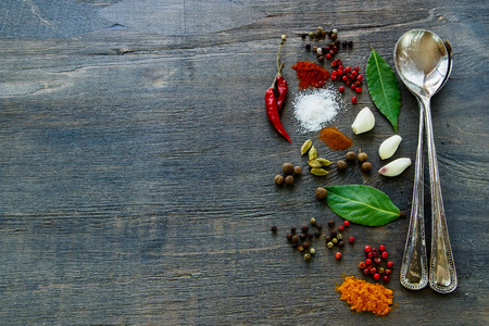 Vintage metal spoons with herbs and spices selection on dark wooden table. Background with space for text.の写真素材