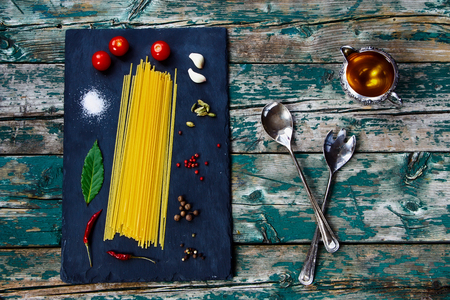 Italian Spaghetti and olive oil, spices and herbs on vintage wooden and slate background.の写真素材