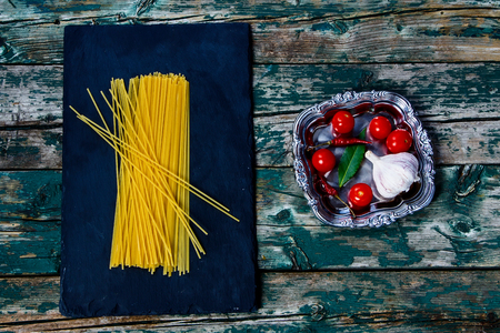 Top view of ingredients for cooking pasta over wooden and slate background.の写真素材