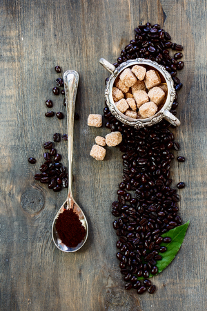 Top view of composition with coffee in vintage spoon and sugar on dark wooden background.の写真素材