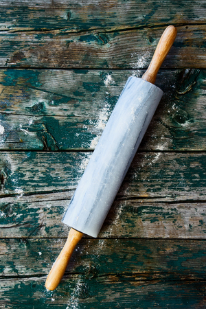 Top view of rolling pin with remnants of flour in a rustic kitchen on an old grainy textured wood surface.の写真素材