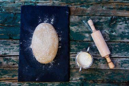 Top view of dough, flour and rolling pin on rustic wooden background. の写真素材