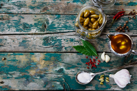 Green olives in jar and Olive Oil on rustic wooden tablel - italian food concept. Background with space for text.の写真素材