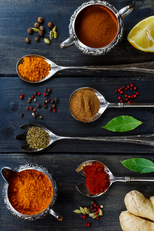Top view of colorful powder spices in old vintage cups and spoons over dark wooden background. Food or cooking concept.の写真素材