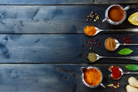 Various powder spices in old metal cups and spoons over dark wooden table. Background with space for text. Food or cooking concept. Top view.の写真素材