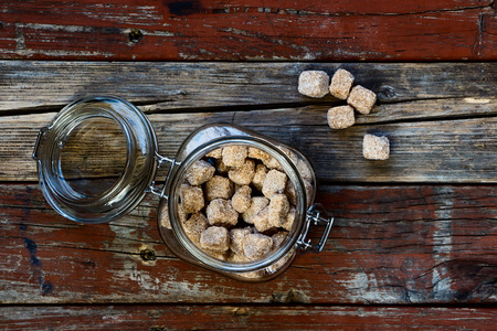 Top view of brown sugar cubes in glass jar on rustic wooden background. Food concept.の写真素材