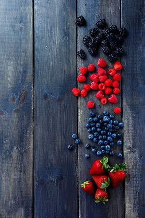 Wood background with Organic spring or summer berries (strawberries, raspberries, blueberries and blackberries). Agriculture, Gardening, Harvest Concept. Top view. Space for text.の写真素材