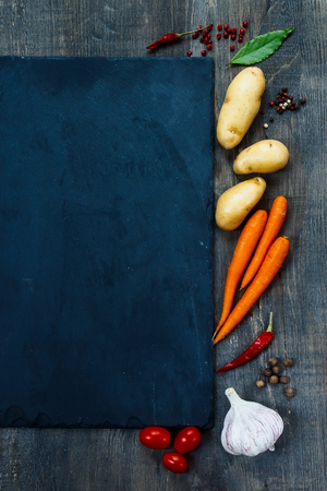 Fresh organic vegetables over slate and dark wooden background with space for text. Healthy food from garden. Top view.の写真素材