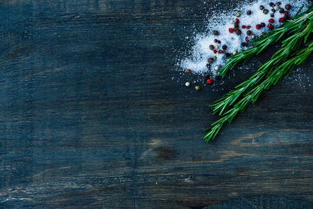 Herbs and spices (rosemary, salt and pepper) on dark wooden background.の写真素材