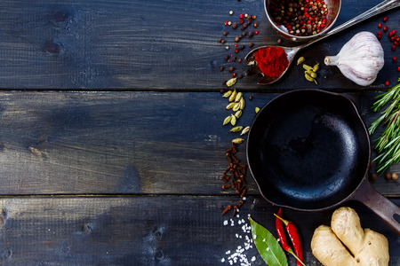 Spices and herbs selection with vintage cast iron skillet on rustic wooden background. Vegetarian food, health or cooking concept.の写真素材