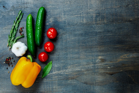 Top view of fresh vegetables and spices on dark wooden background with space for text. Vegetarian food, health or cooking concept.