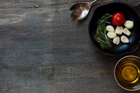 Top view of Italian ingredients in vintage cast iron skillet on rustic wooden background. Vegetarian food, health or cooking concept.の写真素材