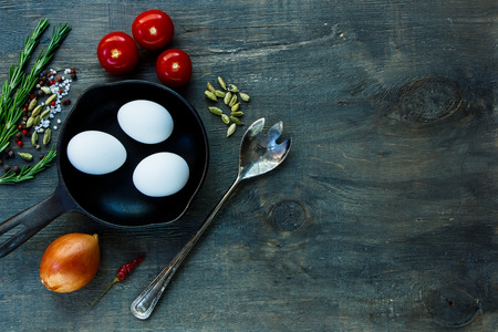 Food background with old cast iron skillet and ingredients on dark wooden board. Vegetarian food, health or cooking concept.の写真素材