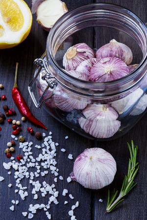 Closeup fresh garlic in glass jar with herbs and spices selection over wood. Harvest or culinary concept.の写真素材