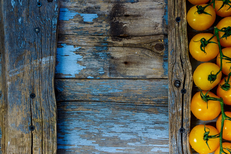 Top view of yellow cherry tomatoes on rustic wooden background with space for text.の写真素材
