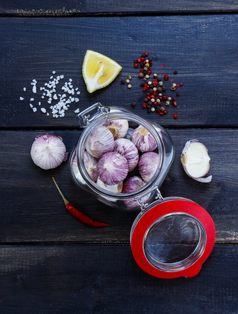 Fresh garlic in glass jar with herbs and spices selection over wood.の写真素材