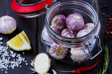 Close up of fresh garlic in glass jar with herbs and spices selection over wood. Harvest or culinary concept.の写真素材