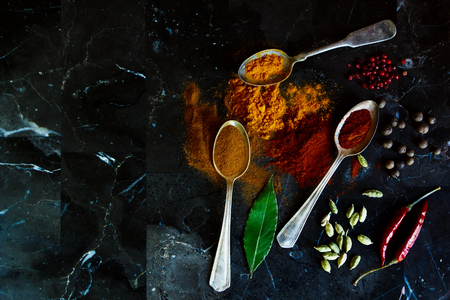Different types of spices in old metal spoons on a stone background with space for text. Top view. Cooking, healthy eating.の写真素材