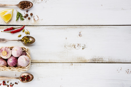 White wooden background with garlic, herbs and spices selection. Space for text. Cooking, food or health concept.