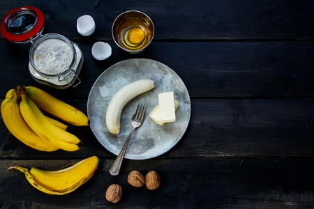Recipe ingredients  (flour in glass jar, eggs and bananas) for baking over rustic wooden board from above. Background with free text space.の写真素材