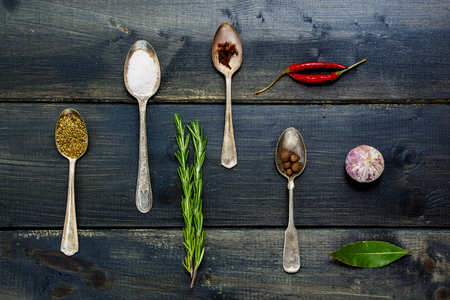 Top view of spices and herbs selection - herbs and spices, old metal spoons and dark wooden background - cooking, healthy eatingの写真素材
