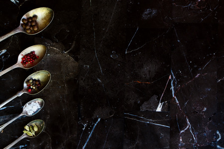 Old metal spoons with spices on a stone background with space for text. Top view. Cooking, healthy eating.の写真素材
