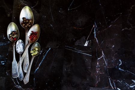 Stone background with spices in old metal spoons. Space for text. Top view. Cooking, healthy eating.の写真素材