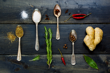 Top view of food elements - herbs and spices, old metal spoons and dark wooden background - cooking, healthy eating.の写真素材