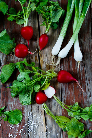 Organic radishes with green onions and salt on rustic wooden background. Health or diet concept.の写真素材