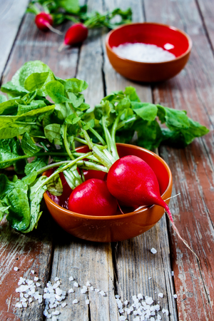 Fresh organic radishes with leaves on rustic wooden background. Selective focus.の写真素材