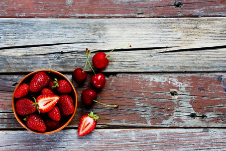 Strawberries in bowl on rustic wooden background with space for text.の写真素材