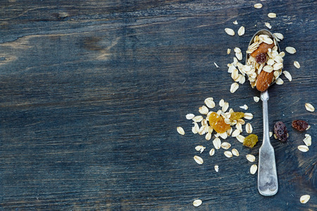 Healthy breakfast - muesli in old metal spoon over dark wooden background with space for text. Health and diet concept.の写真素材