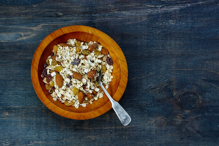 Healthy breakfast - muesli in wooden bowl over dark background with space for text. Health and diet concept.の写真素材