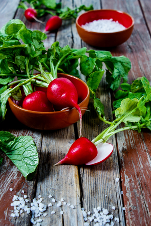 Bright organic radishes with leaves on rustic wooden background. Selective focus.の写真素材