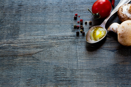 Fresh tomatoes, olive oil and mushrooms on dark wooden background with space for text. Vegetarian food, health or cooking concept.の写真素材