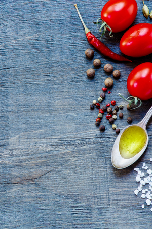 Fresh tomatoes with herbs and spices on dark wooden background with space for text. Vegetarian food, health or cooking concept.の写真素材