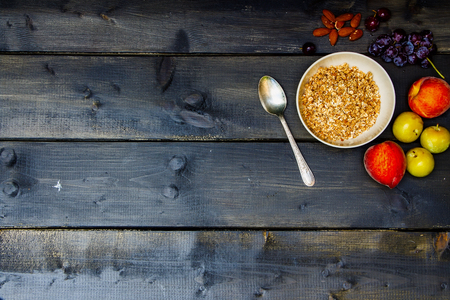 Fresh fruits, almonds and homemade granola for breakfast on old wooden background with space for text. Health and diet concept.の写真素材